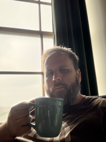 Robert James Sullivan holding a mug by a sunlit window