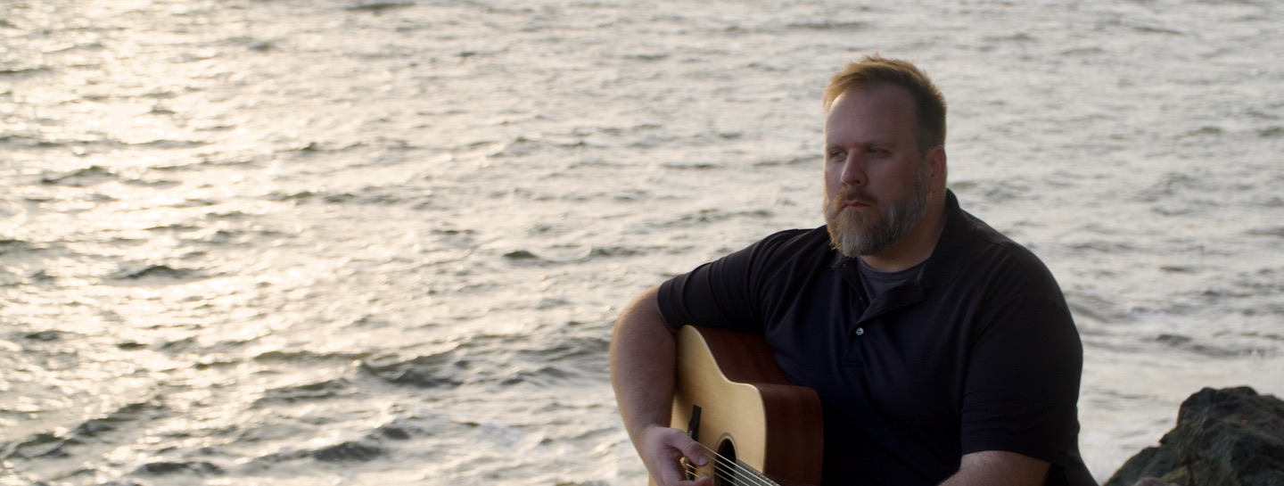 Robert Sullivan with guitar at the waterfront